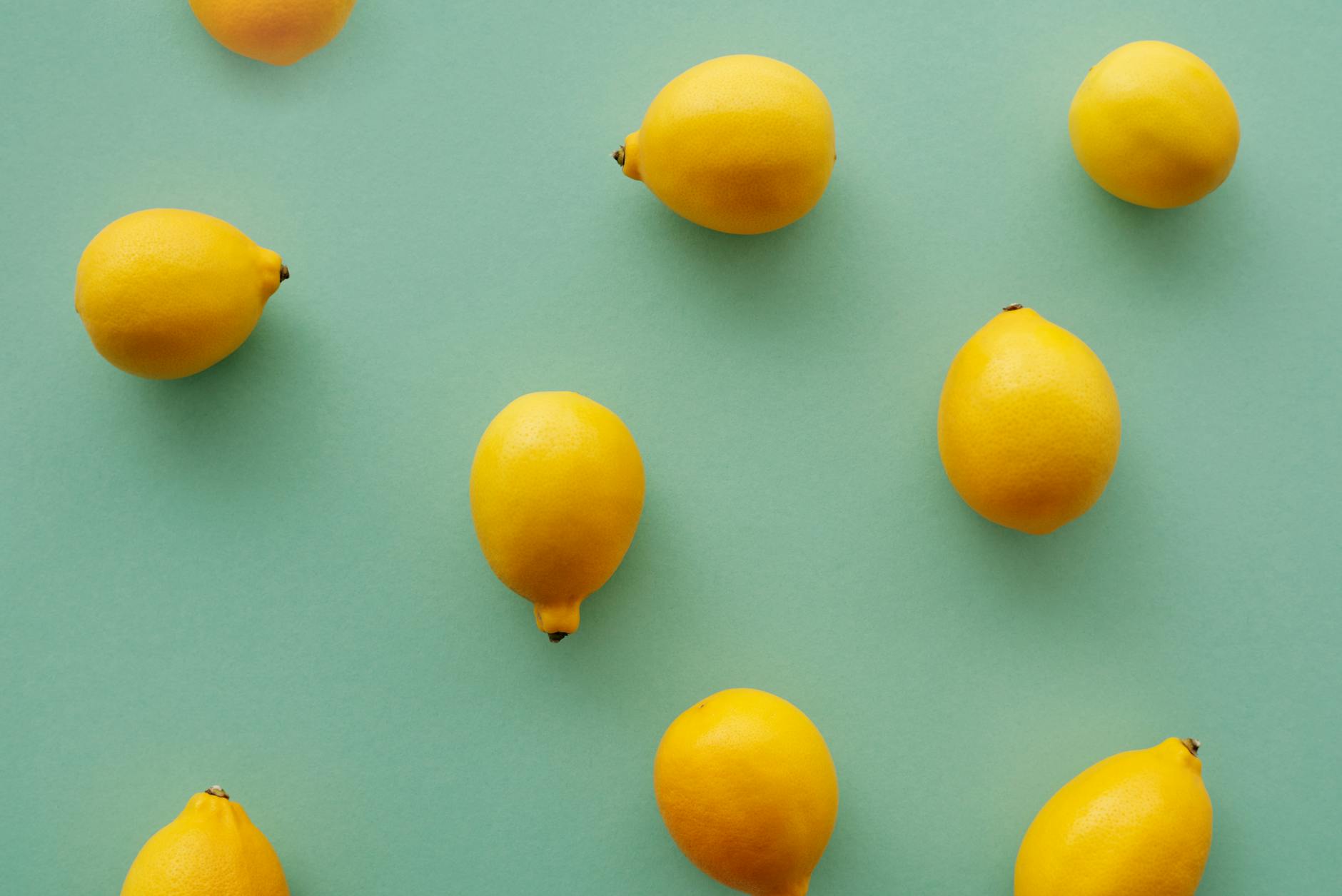 Limones brillantes dispuestos sobre un fondo pastel verde, creando una composición fresca y vibrante