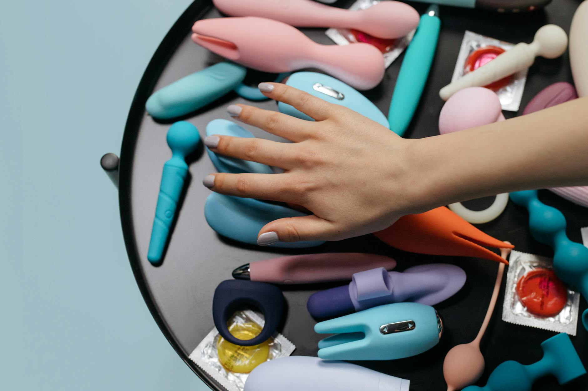 Close-up of hands holding a sleek blue vibrator against a purple background