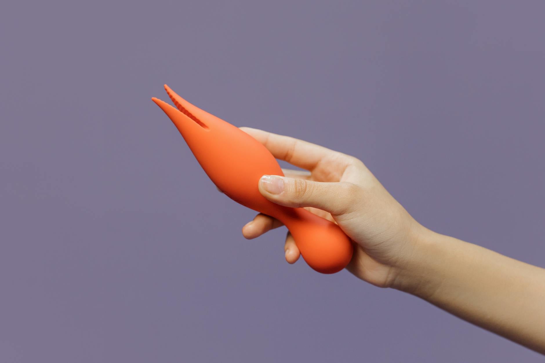 A hand holding a lemon-colored vibrator against a minimalistic purple backdrop, showcasing modern sensuality and confidence.